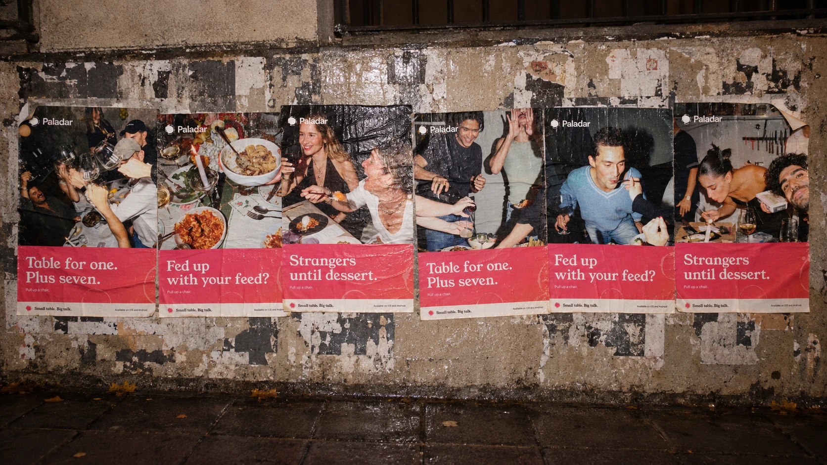 Six Paladar posters pasted on a street wall at night. They read: Table for one. Plus seven. Fed up with your feed? Strangers until dessert.